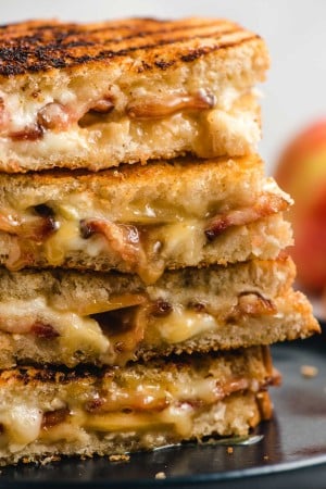 Stack of Brie Grilled Cheese that shows the gooey cheese and bacon on the inside.