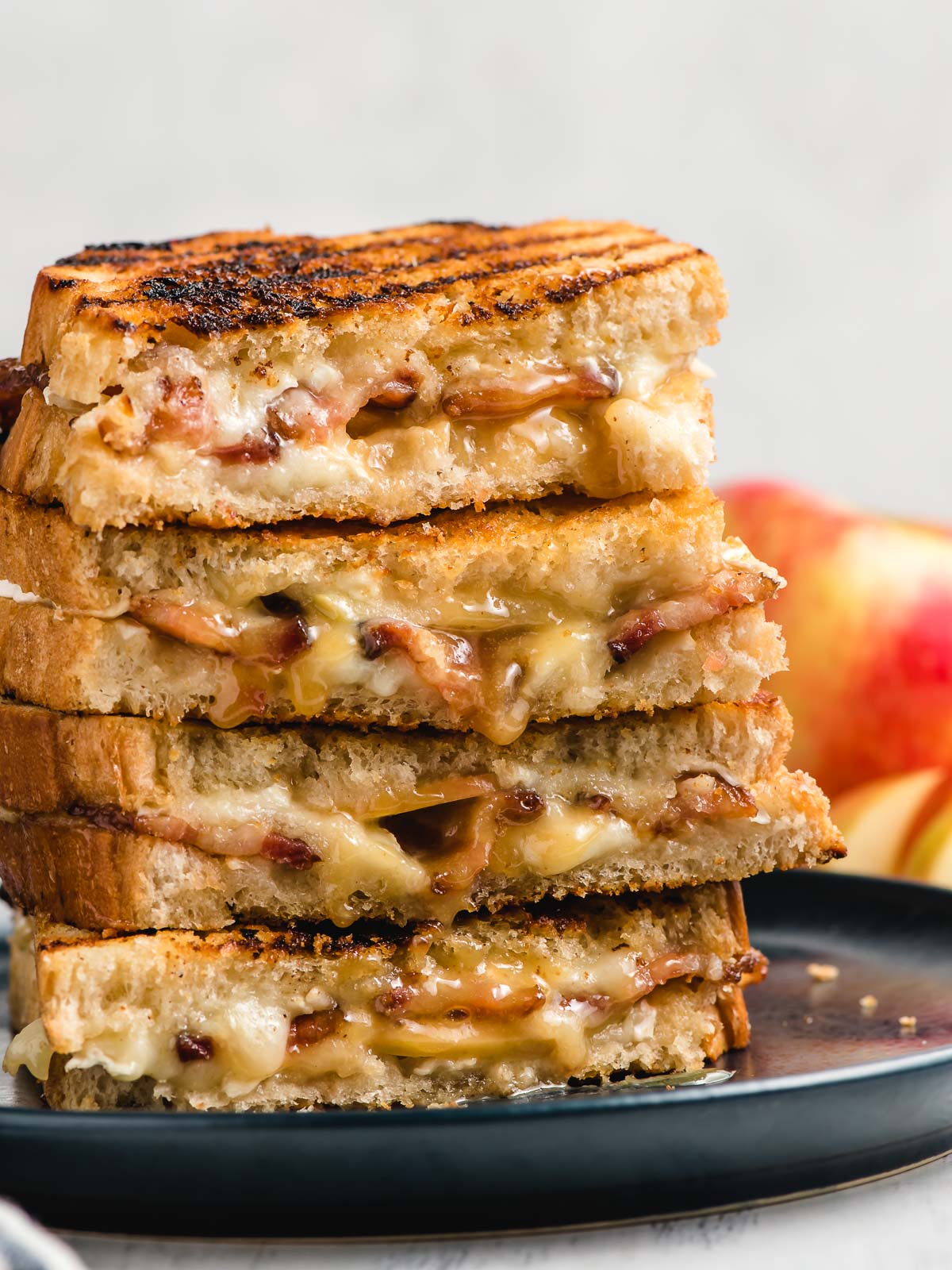 Stack of grilled cheese with brie, bacon, and apple slices.