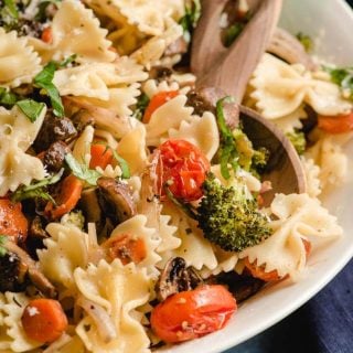Wooden spoon scooping Roasted Veggie Pasta out of a large bowl.