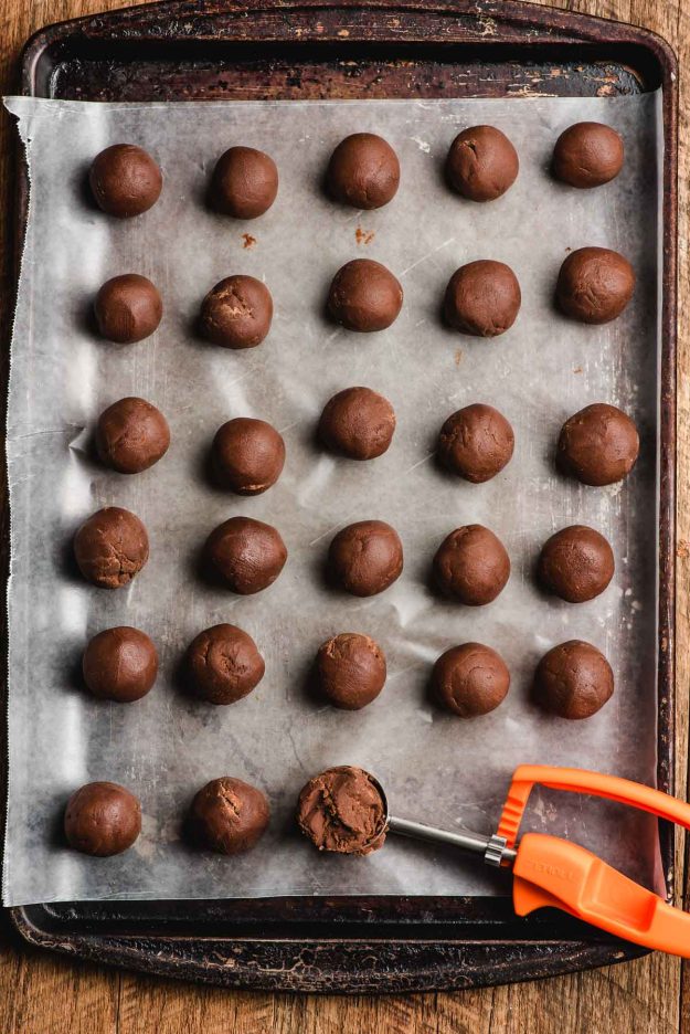 Truffle balls scooped out onto a baking sheet lined with wax paper.