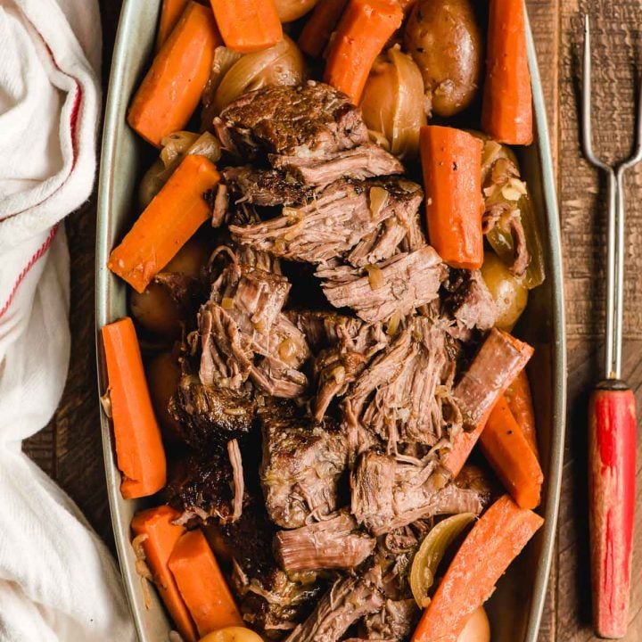 Large rectangular platter stacked with carrots, potatoes, and beer pot roast.