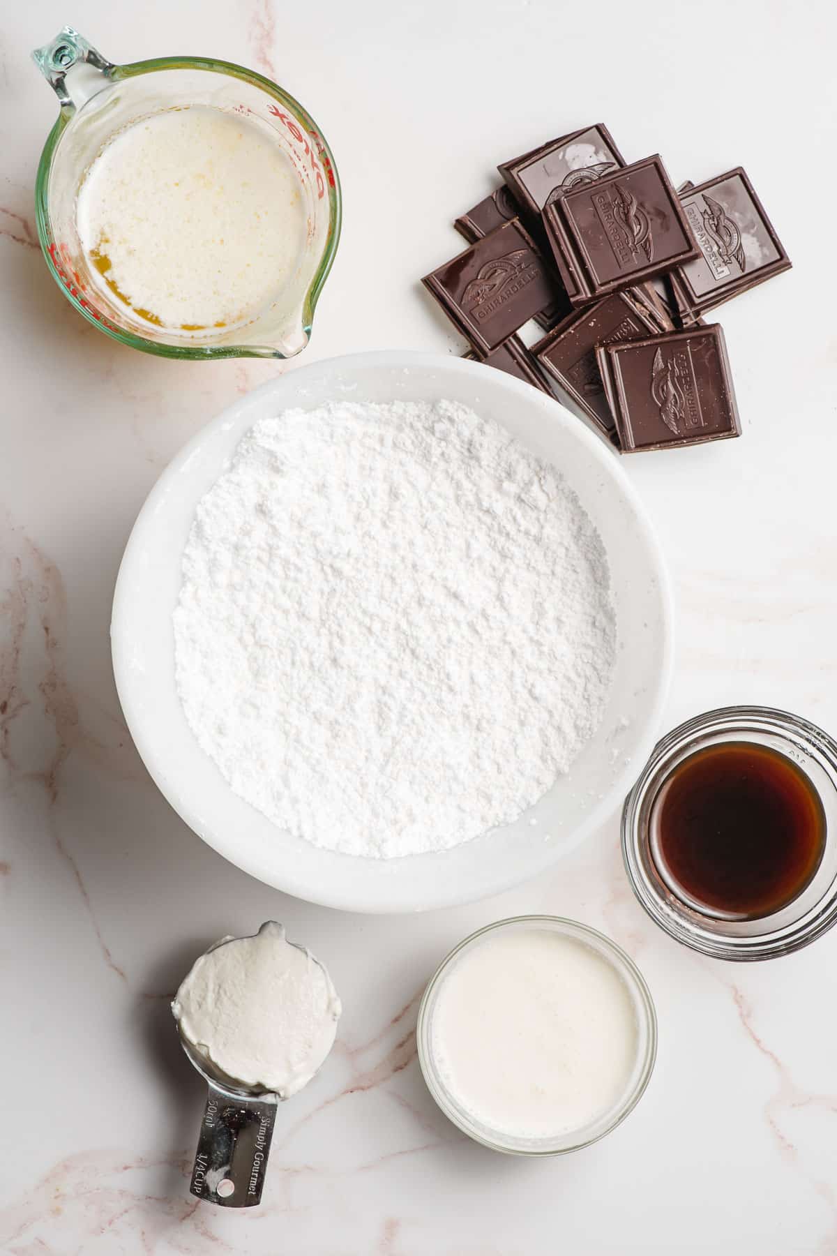 Chocolate sour cream glaze ingredients, shown in prep bowls on a marble background.