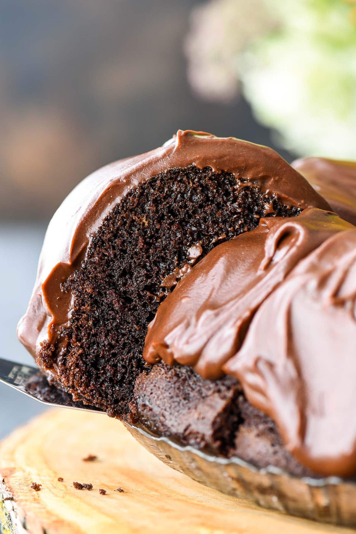 Slice of moist chocolate bundt cake held out by a spatula.