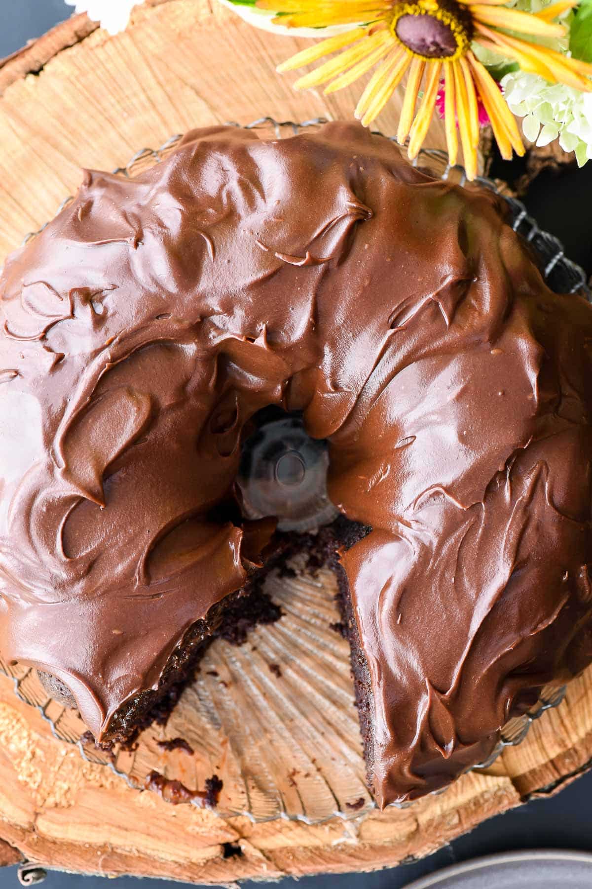 Top down image of a frosted chocolate bundt cake on a wood background.