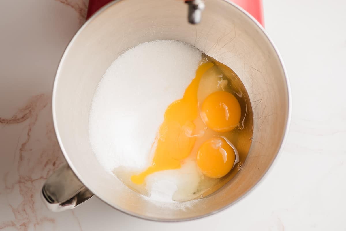 Eggs, sugar, baking soda, salt, and oil in the bowl of an electric mixer.
