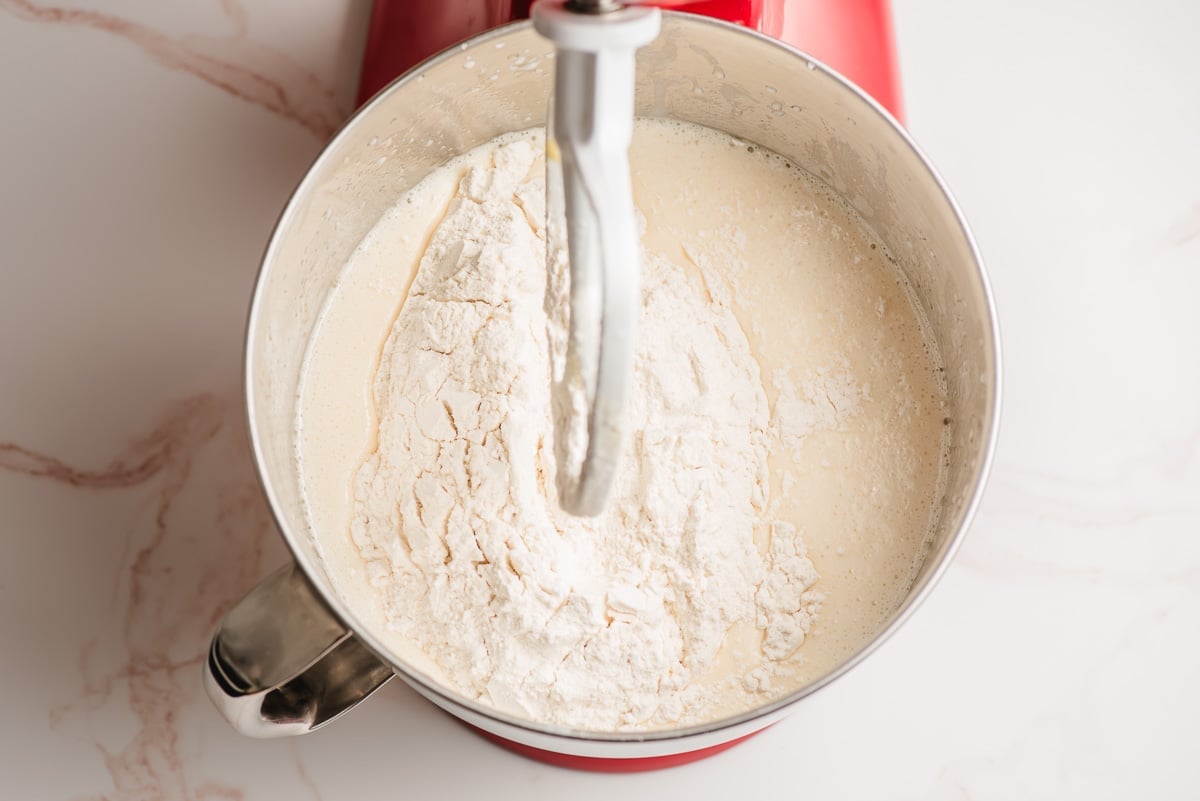 Flour added to a cake batter mix in the bowl of an electric mixer.