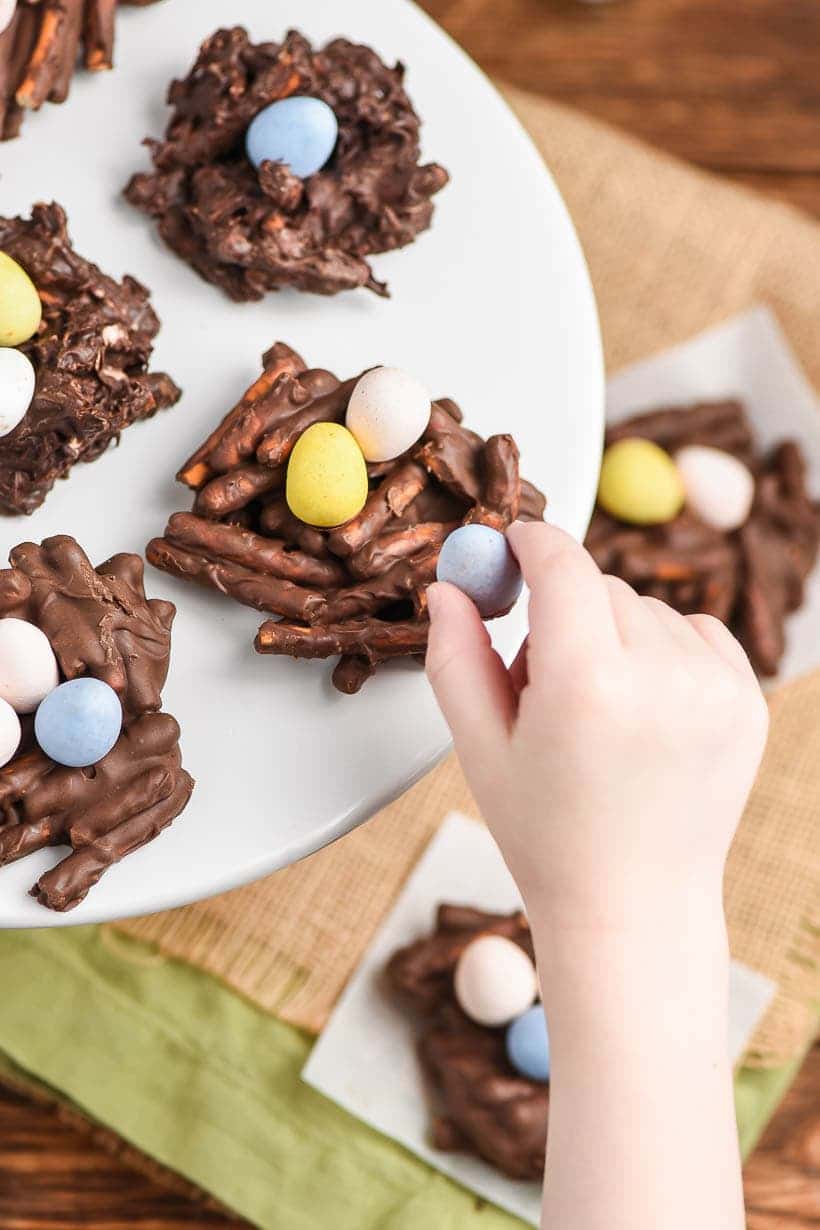 Chocolate Easter Nests with a child's hand grabbing a chocolate egg from the nest