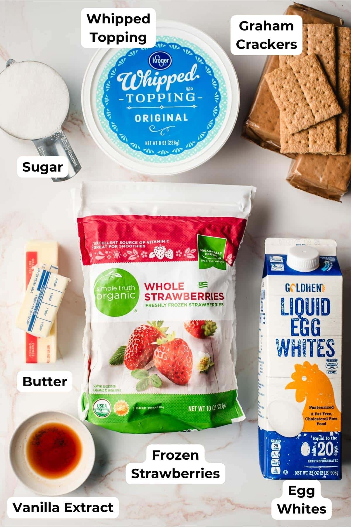 Sugar, whipped topping, graham crackers, 1 1/2 sticks butter, frozen strawberries, vanilla extract, and a carton of pasteurized egg whites on a counter top.