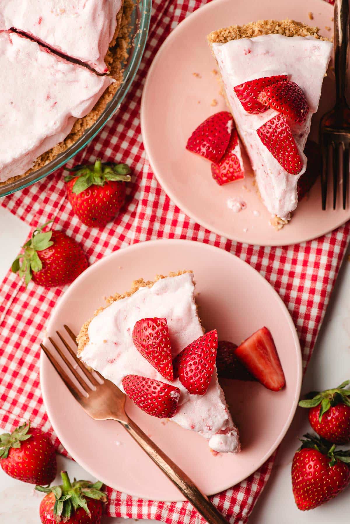 Two pink plates, each topped with a slice of frozen strawberry mousse pie.