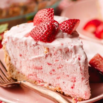 Slice of frozen strawberry pie topped with sliced strawberries.