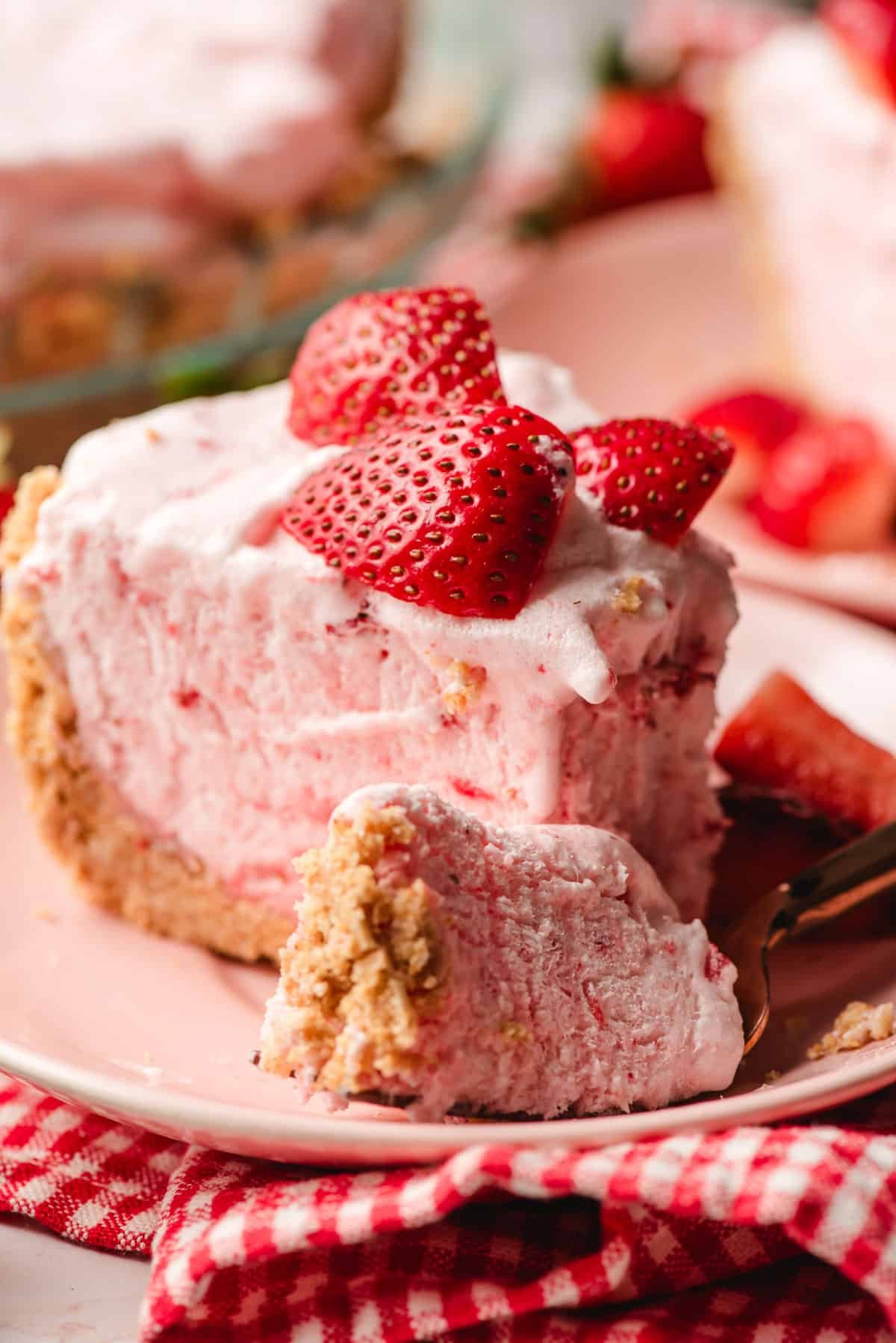 Slice of frozen strawberry pie with a fork taking a bite off it.