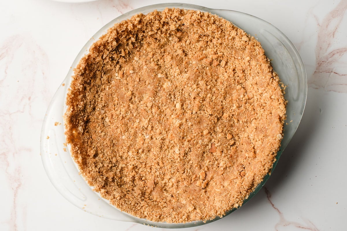 Graham cracker crust in a deep dish glass pie pan.