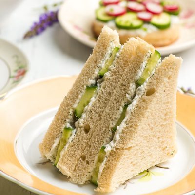 triangle cucumber sandwiches on a yellow rimmed plate