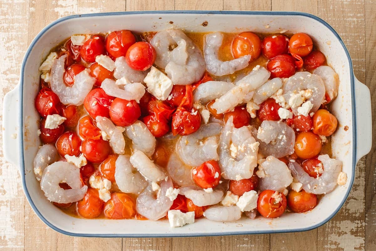 Roasted tomatoes tossed with shrimp, feta, and lemon juice in a baking dish.