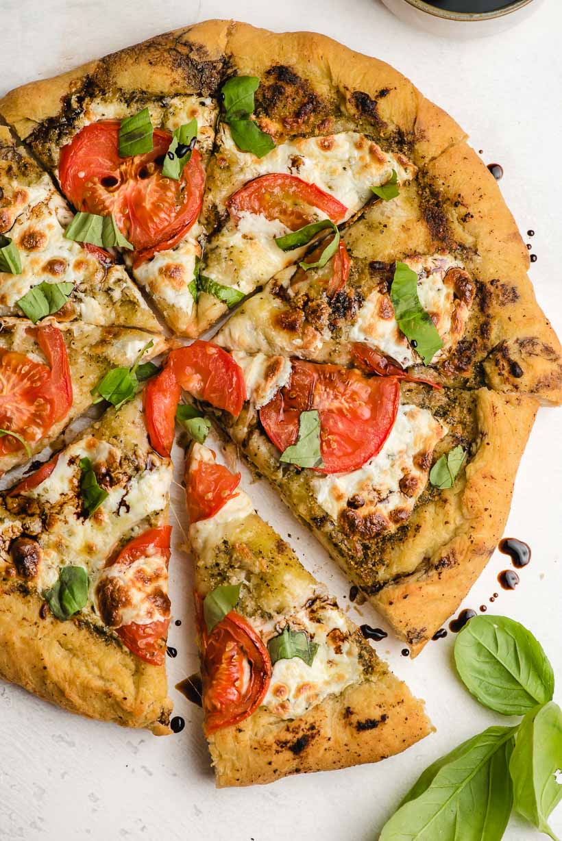 slice caprese pizza and fresh basil leaves