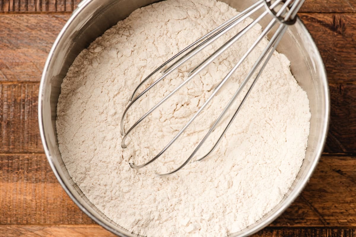 Flour, baking powder, and pumpkin pie spices whisked together in a bowl.