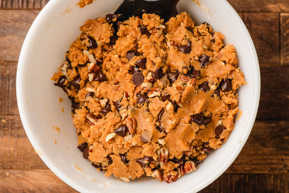 Pumpkin cookie dough with chocolate chips and pecans in a white bowl.