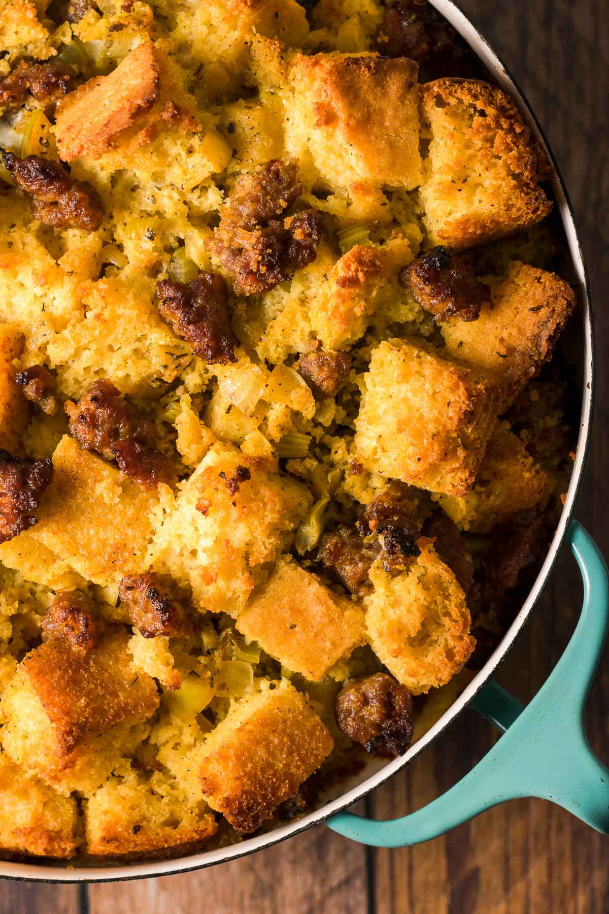 Toasty brown cornbread cubes and sausage shown in a round casserole dish.