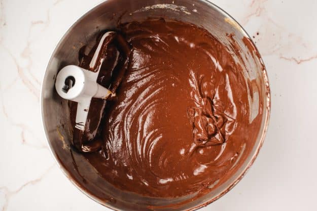 Melted chocolate mixed into cookie batter in a mixing bowl.