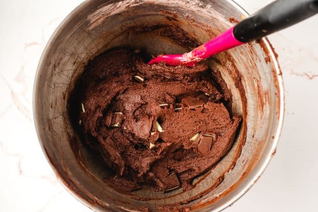 Brownie cookie batter studded with Andes mints in a mixing bowl.