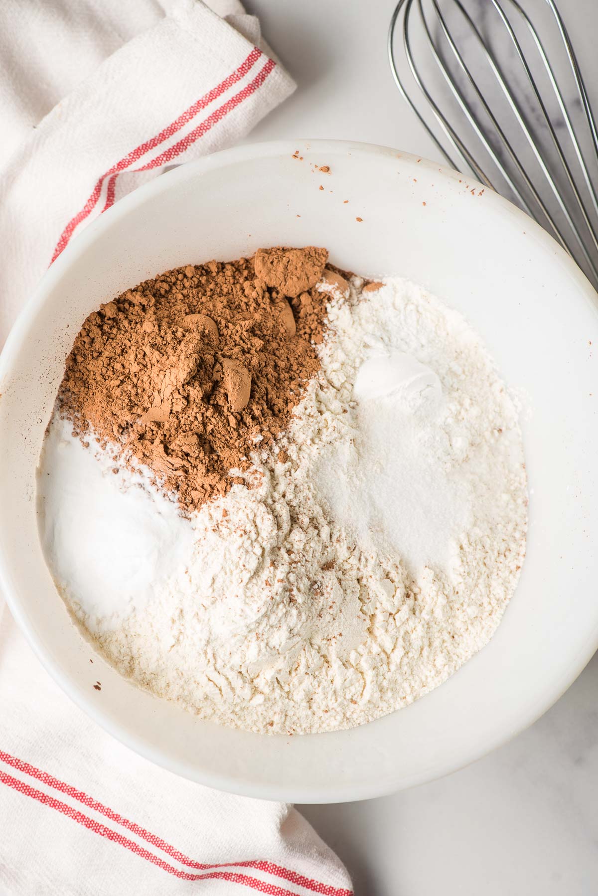 White mixing bowl with flour, cocoa powder, salt, and baking powder.