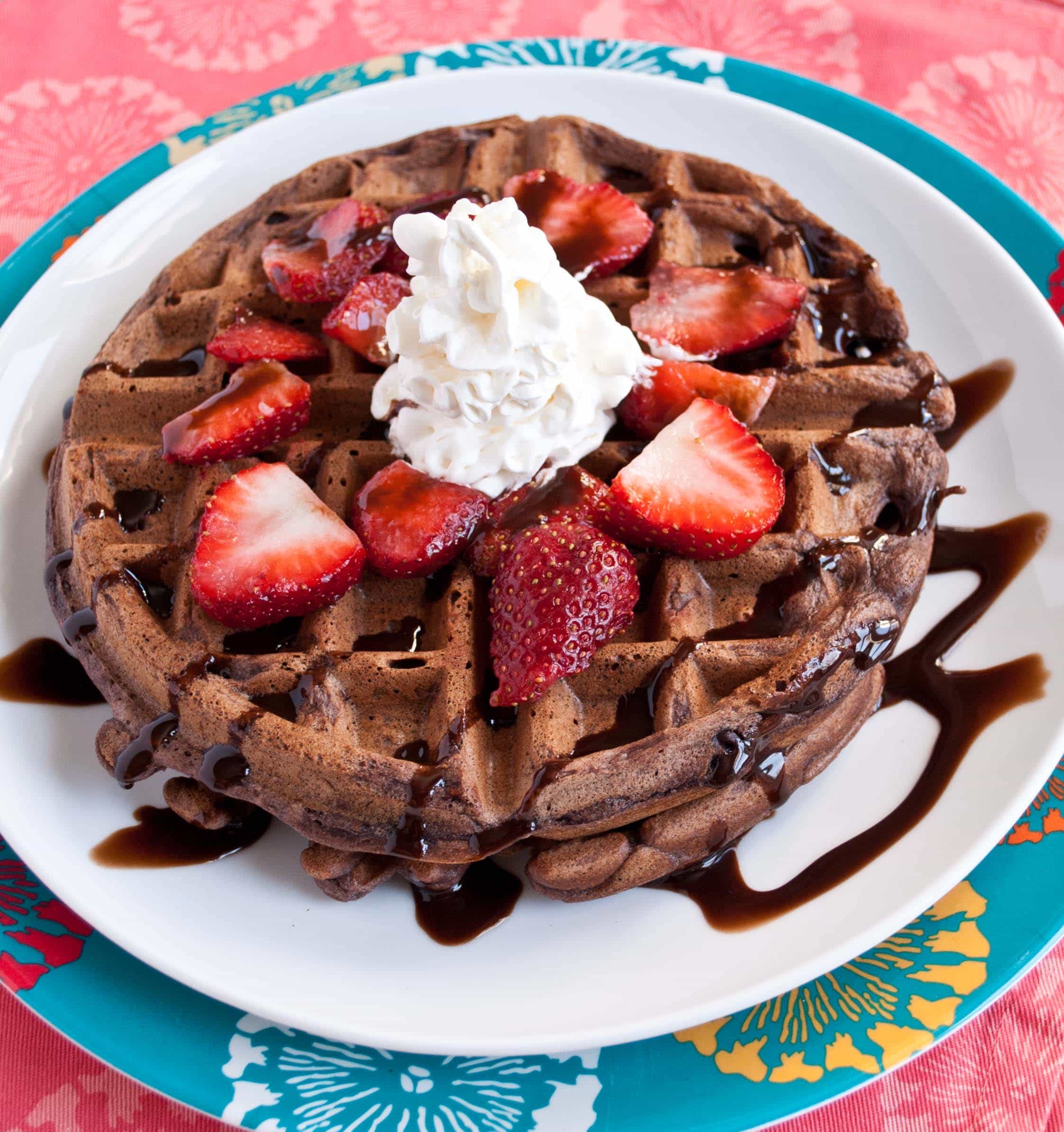 chocolate chip waffle with strawberry slices and dollop of whipped cream