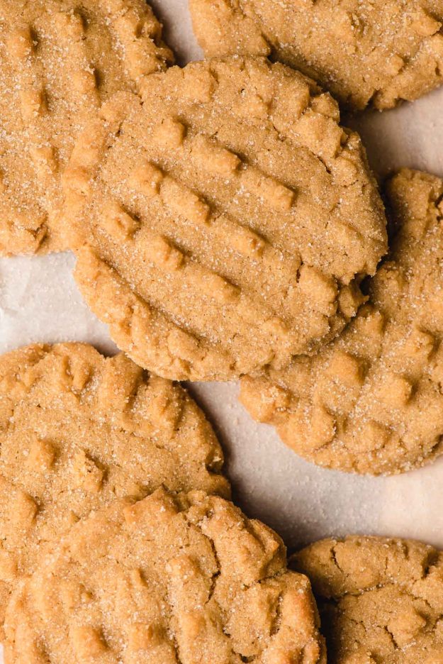 Peanut butter cookies overlapping each other on a parchment paper background.