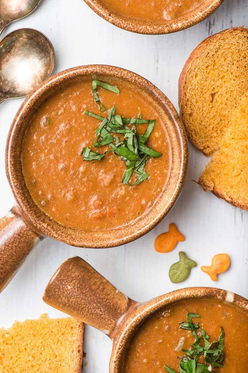 two brown bowls filled with vegetarian lentil soup, topped with basil