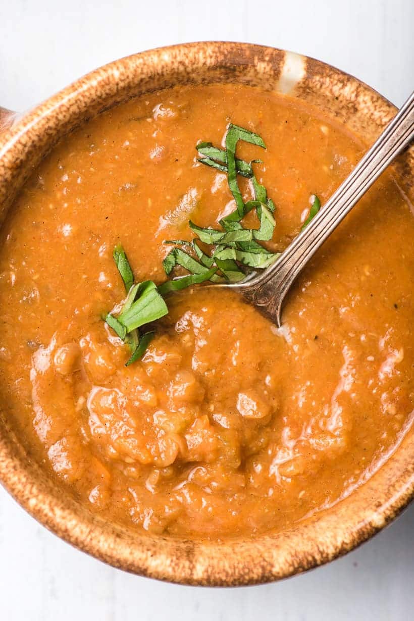 bowl of healthy lentil soup with basil and a spoon