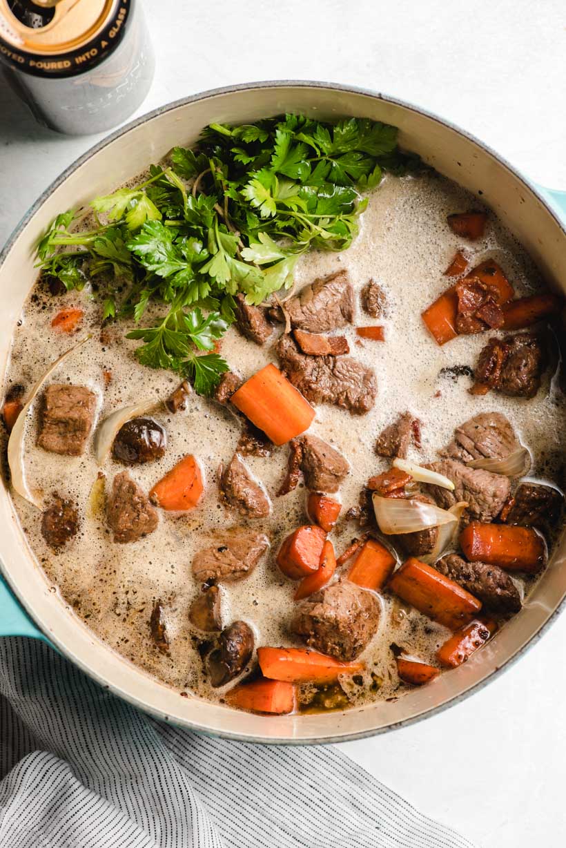 Guiness Beef Stew pictures in a Dutch oven before going into the oven. The beer is still frothy on the top.