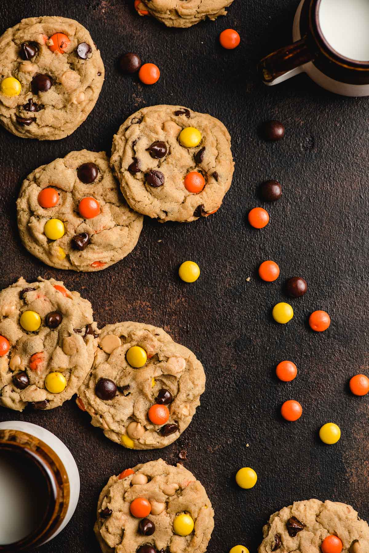 Reese's Pieces Cookies with mugs of milk on a black background.