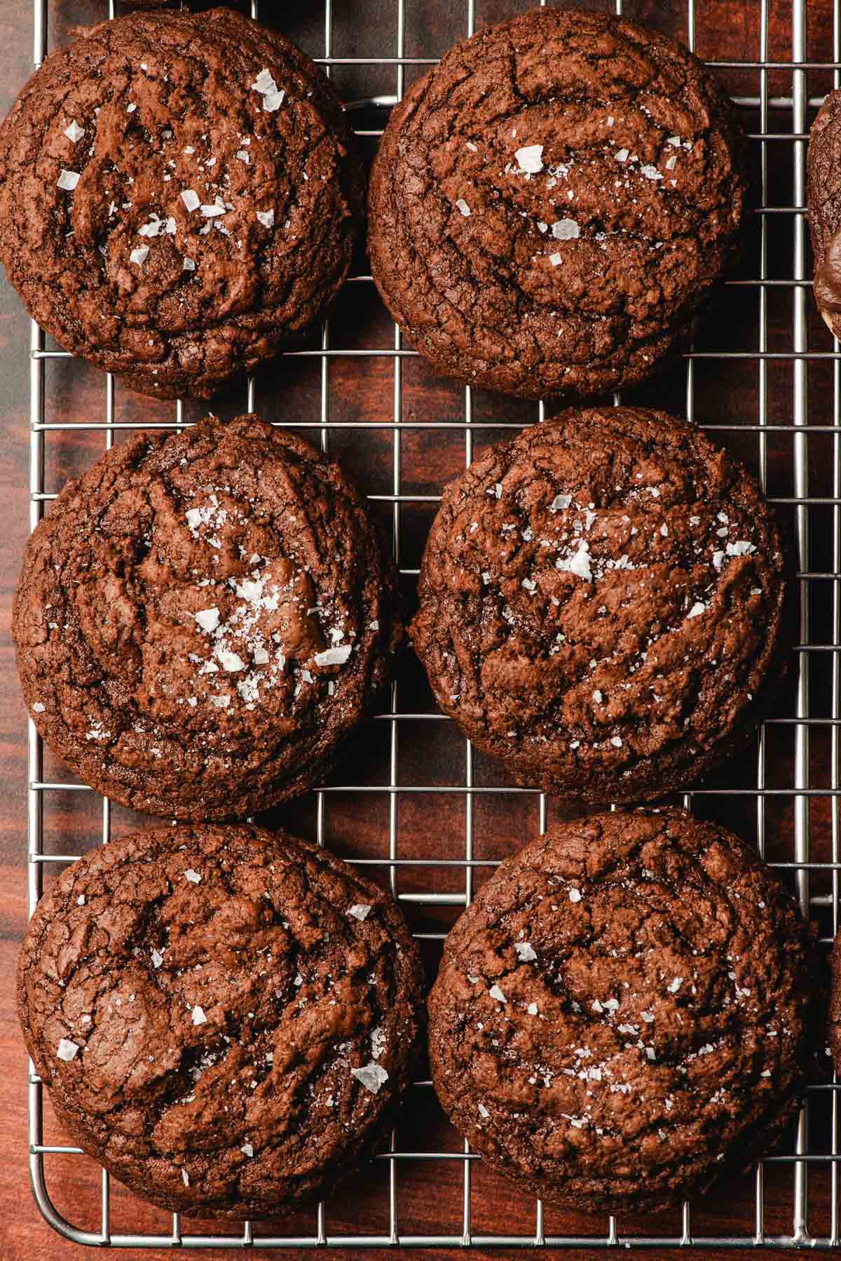 Double chocolate brownie cookies on a cooling rack, sprinkled with salt.