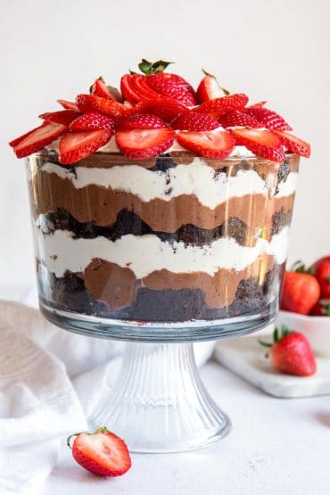 Layered Chocolate Punch Bowl Cake topped with sliced strawberries.