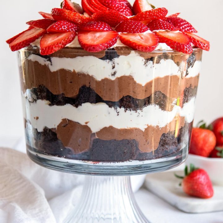 Layered Chocolate Punch Bowl Cake topped with sliced strawberries.