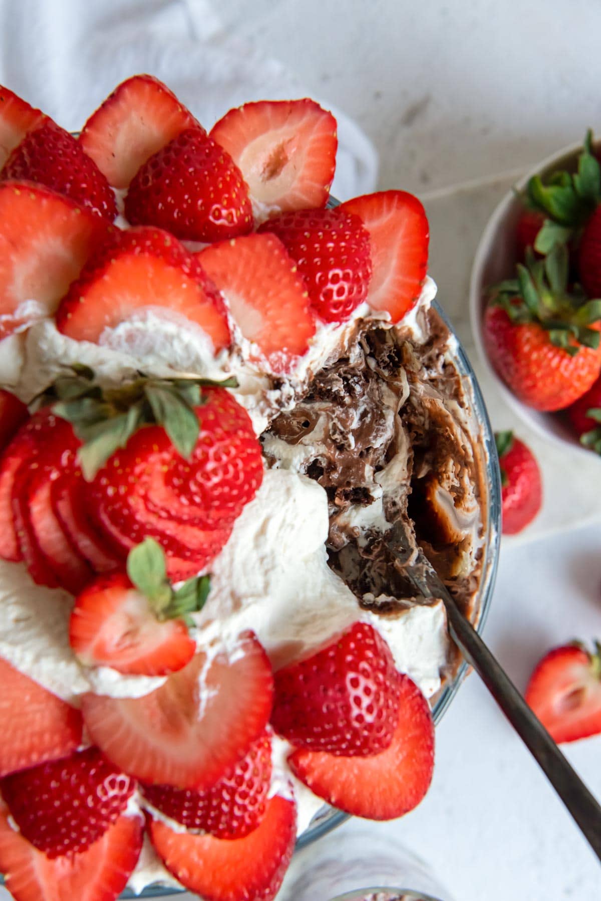 Top down image of a strawberry chocolate punch bowl cake with a scoop taken out of it.