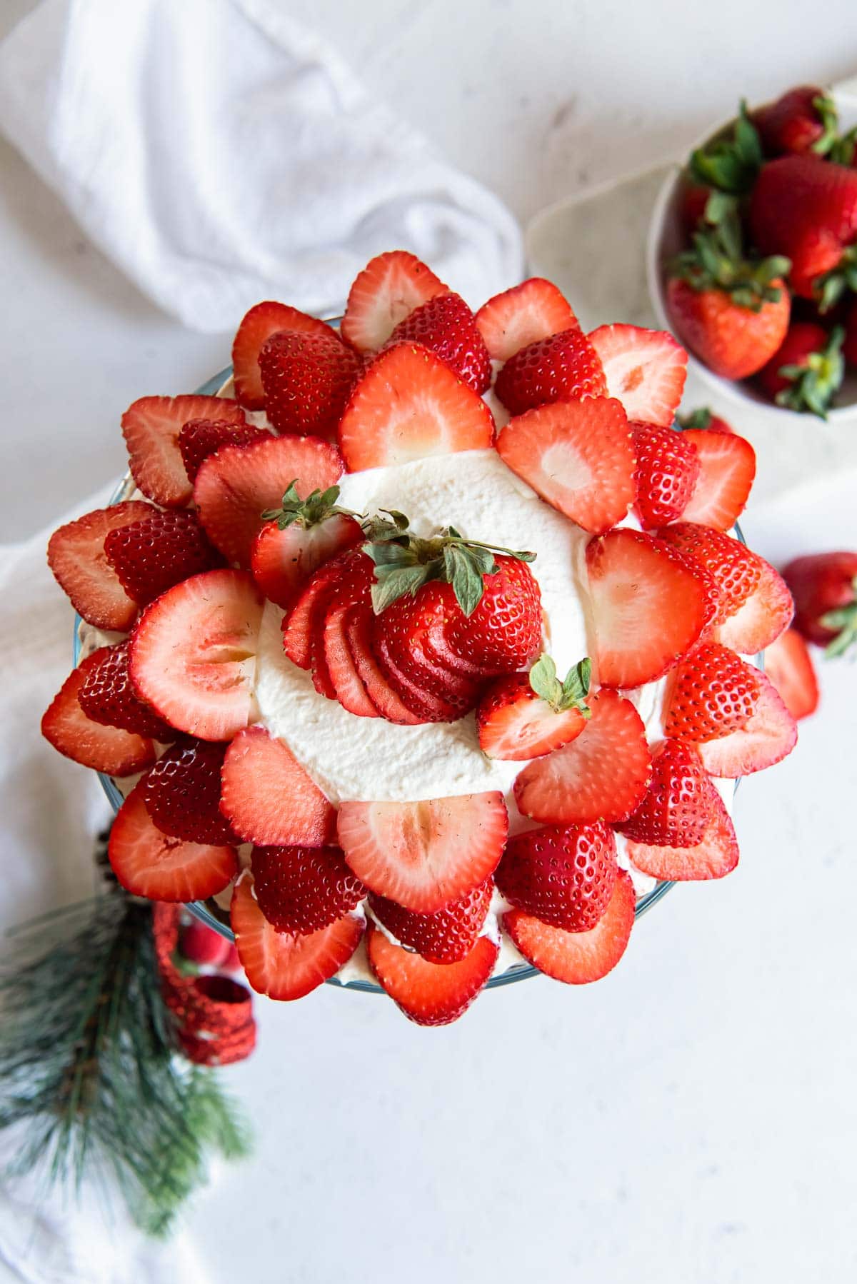 Strawberries arranged in a pretty circular design on top of a punch bowl cake.