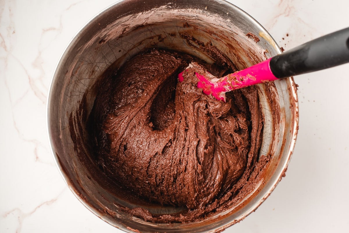 Brownie cookie batter in a mixing bowl with a spatula.