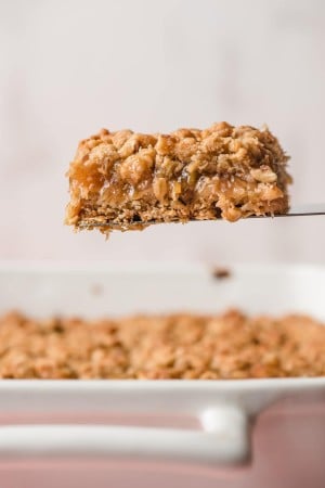 Spatula holding a rhubarb bar above a dish.