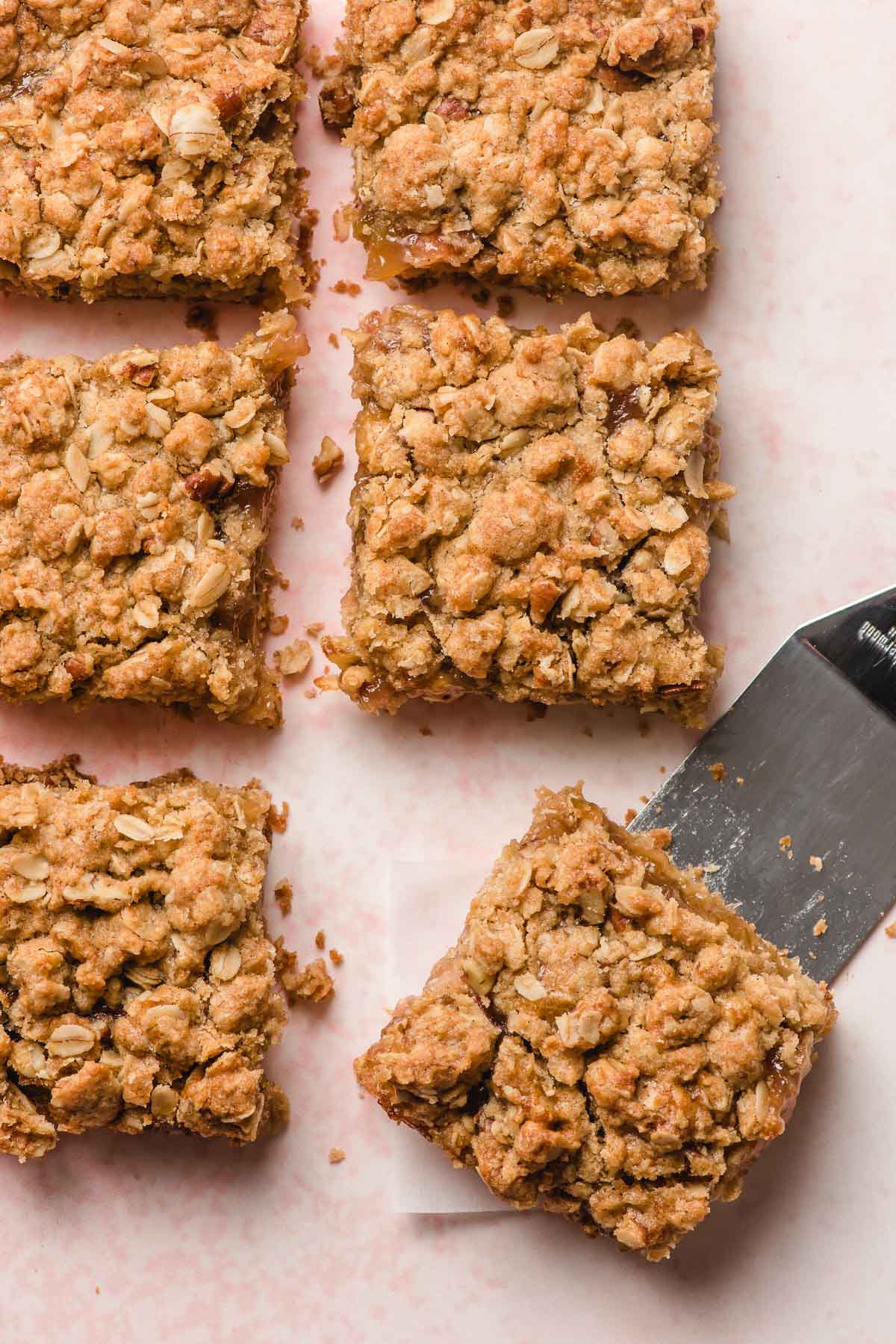Rhubarb bars lined up in a row, with a spatula under one piece.