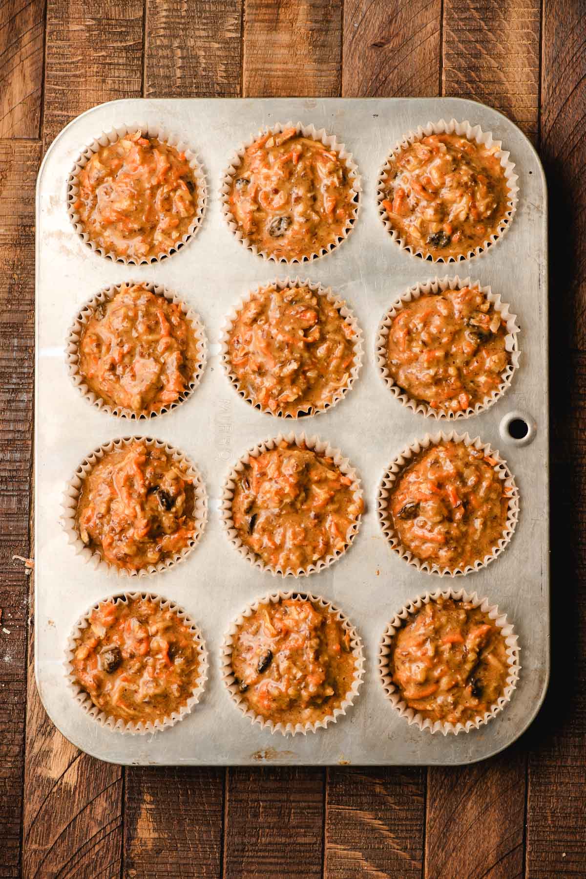 Morning glory muffin batter in a muffin tin.