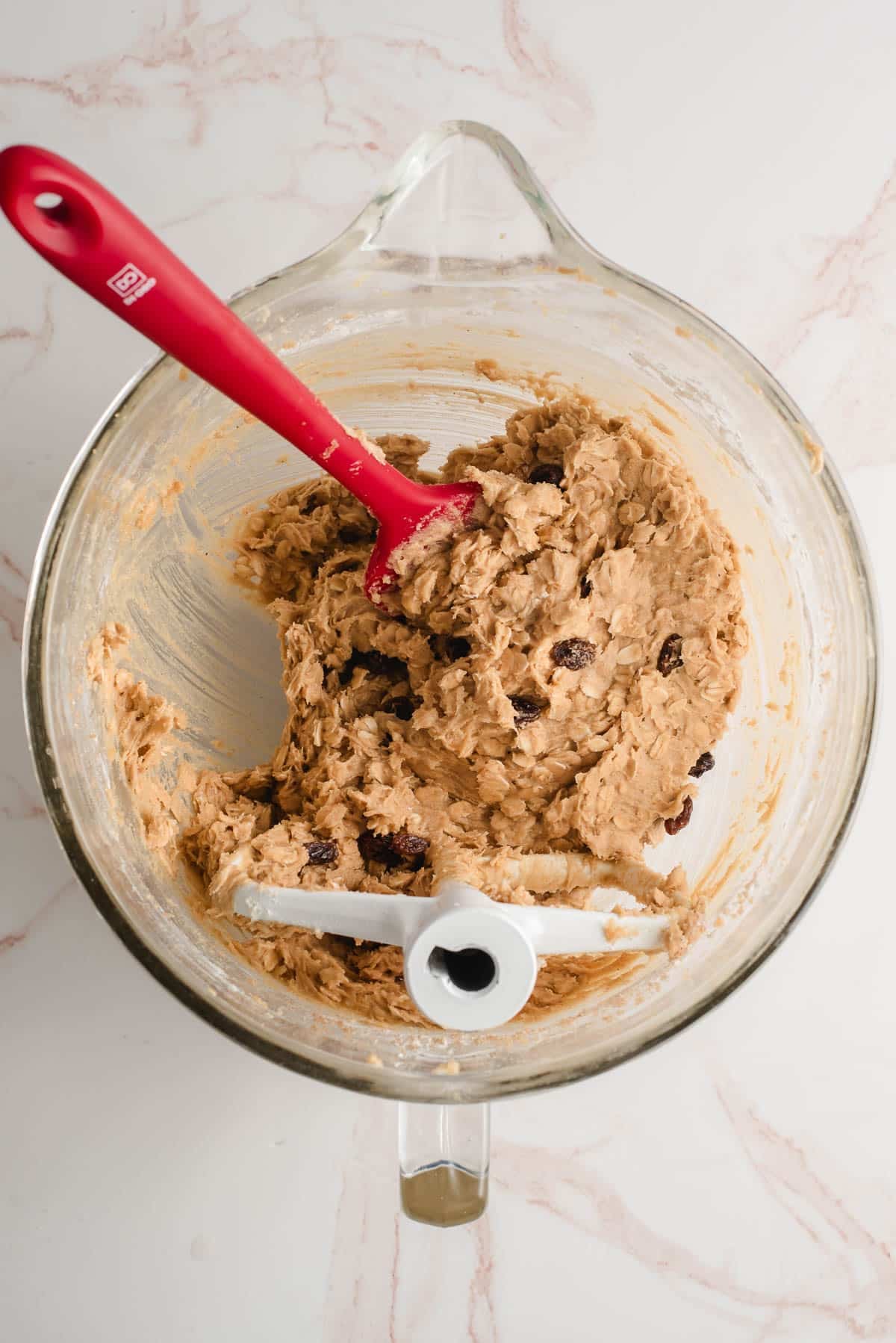 Oatmeal raisin cookie dough in a glass mixing bowl.