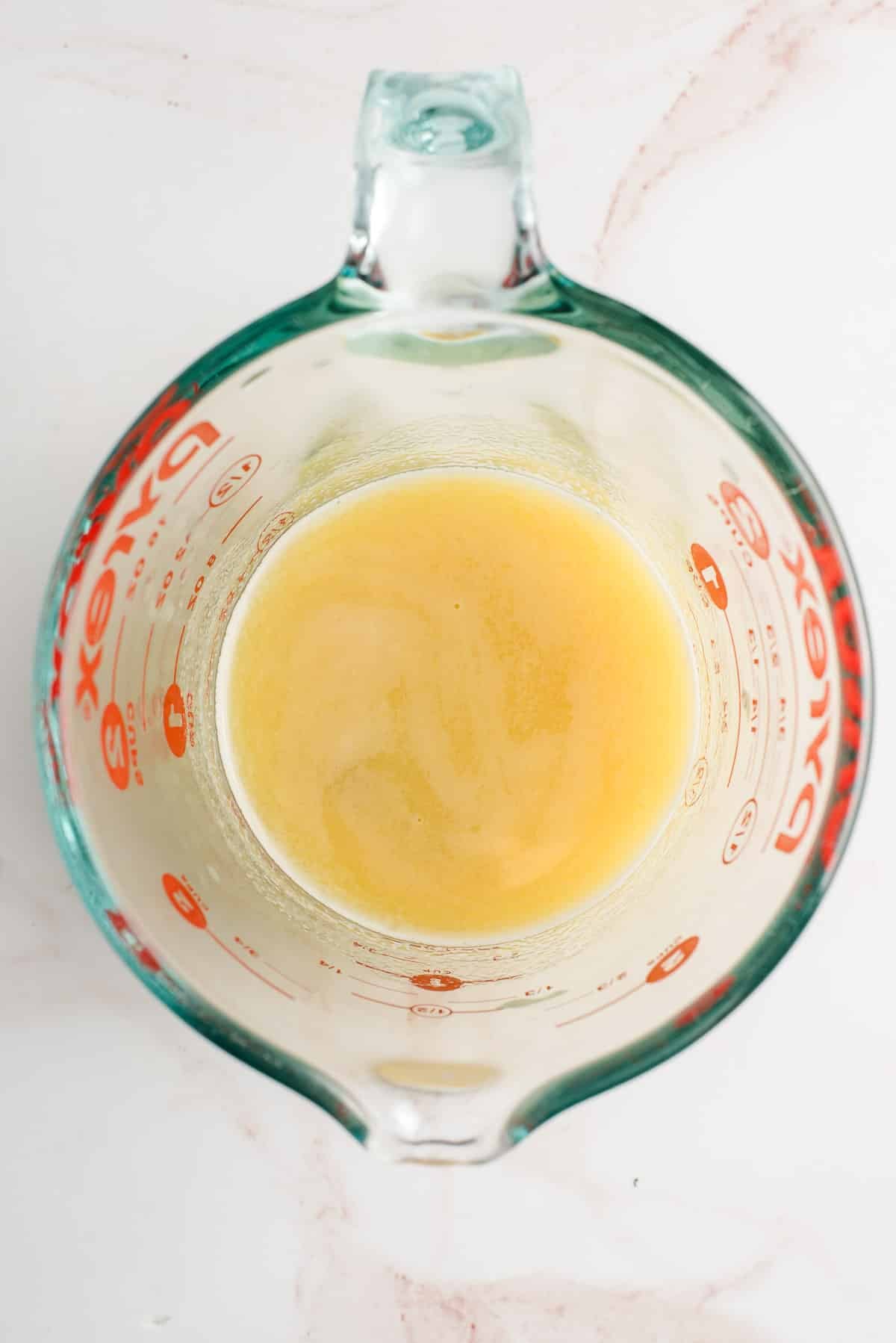 Raisins soaking in orange juice in a measuring cup.