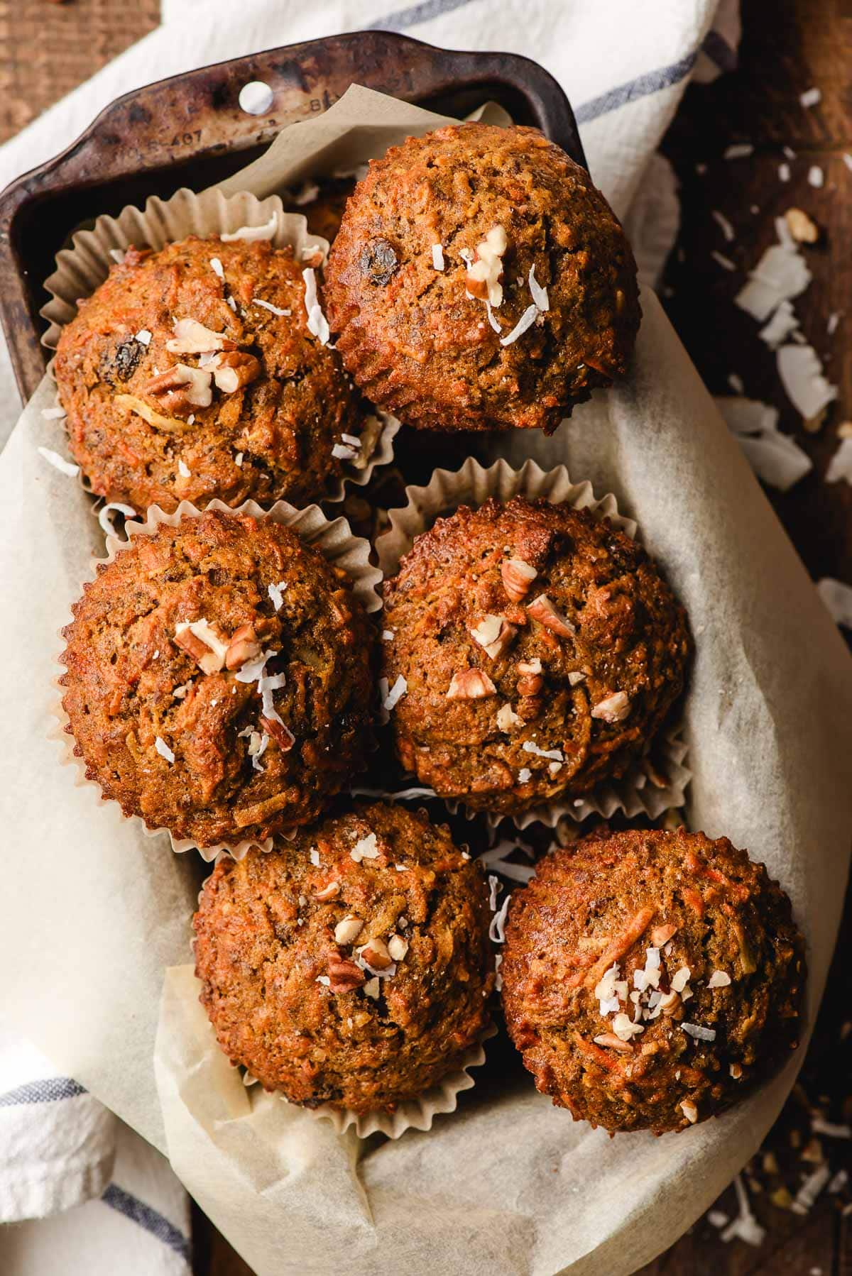Old loaf pan filled with morning glory muffins topped with shredded coconut.