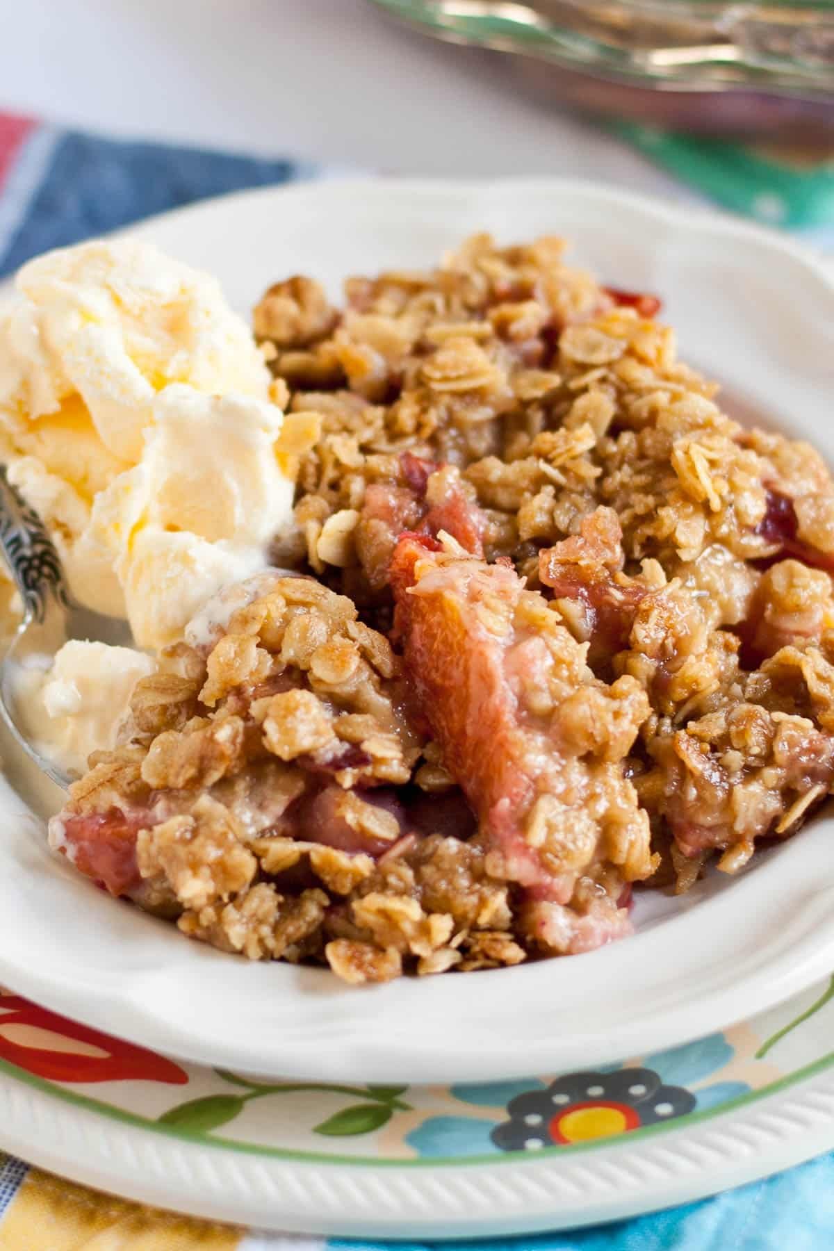 Cherry, strawberry, and nectarine crisp in a bowl with a scoop of ice cream.