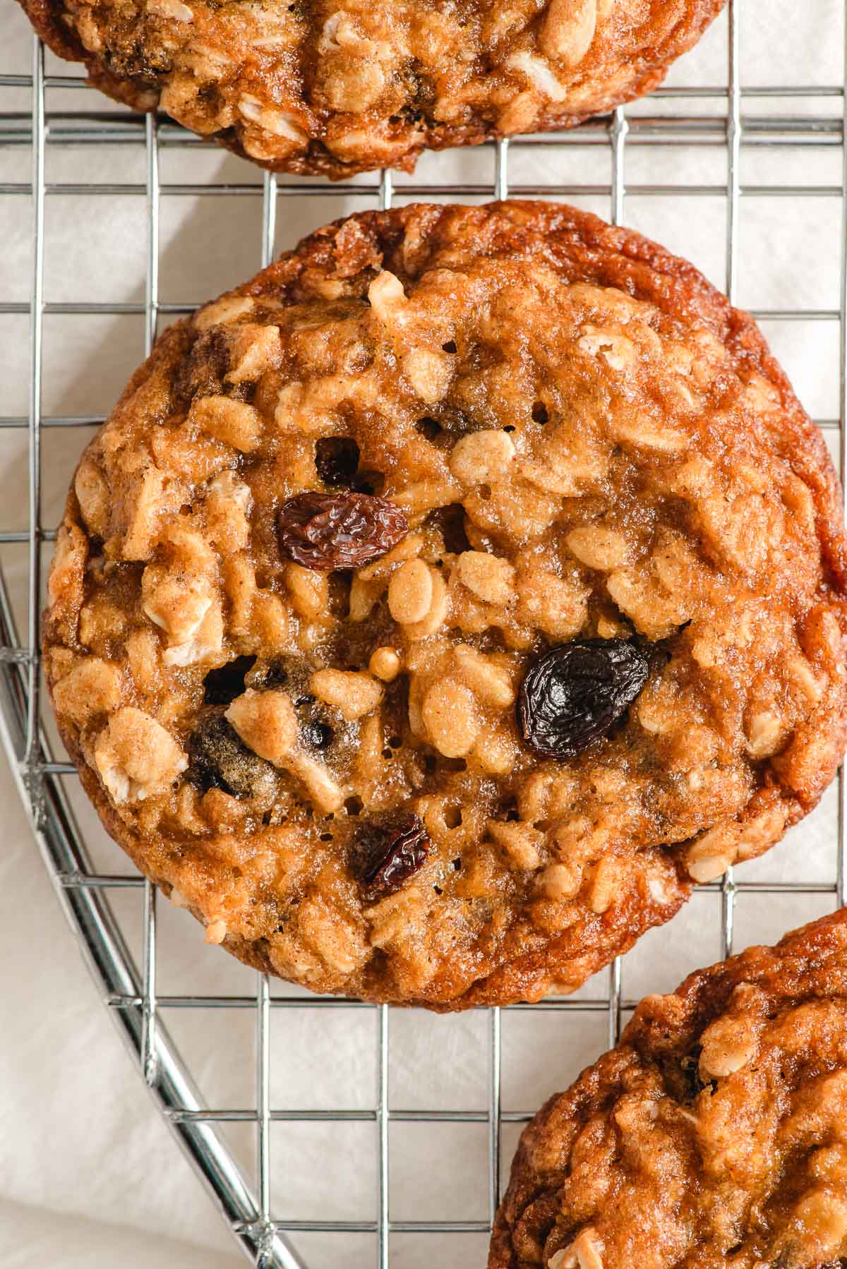 Freshly baked oatmeal raisin cookie on a cooling rack.