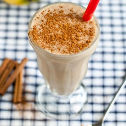 Peanut butter banana smoothie in a tall shake glass with cinnamon sprinkled on top.