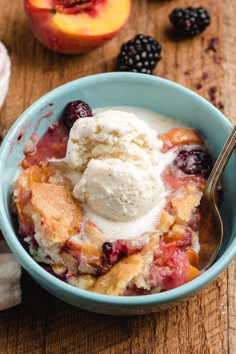 scoop of blackberry peach cobbler in a bowl with ice cream