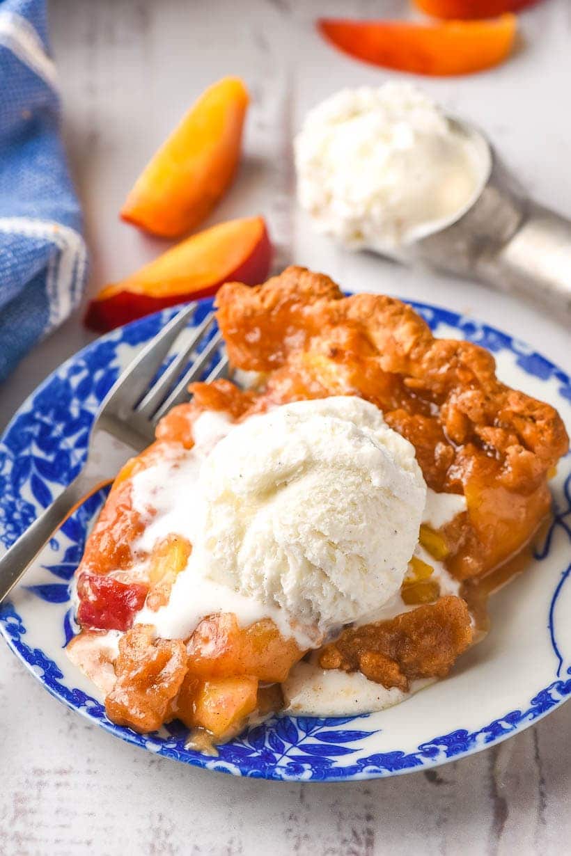 Slice of Peach Crumble Pie with a scoop of ice cream on top