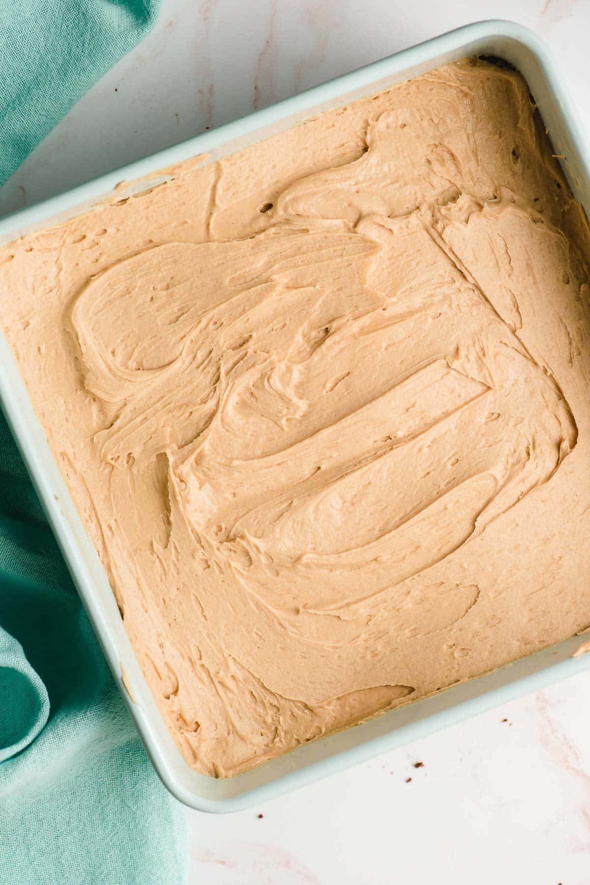 Creamy peanut butter filling spread over a pan of brownies.