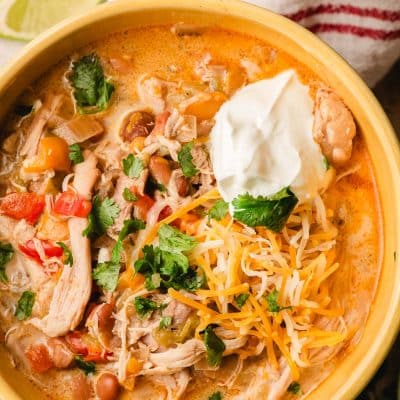 Bowl of slow cooker white chicken chili with sour cream and shredded cheese.